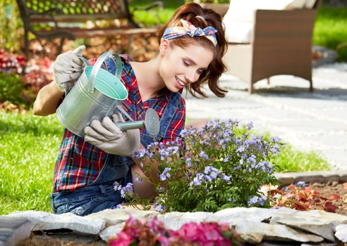 Professional gardener maintaining a Park Royal garden with lawn and hedges